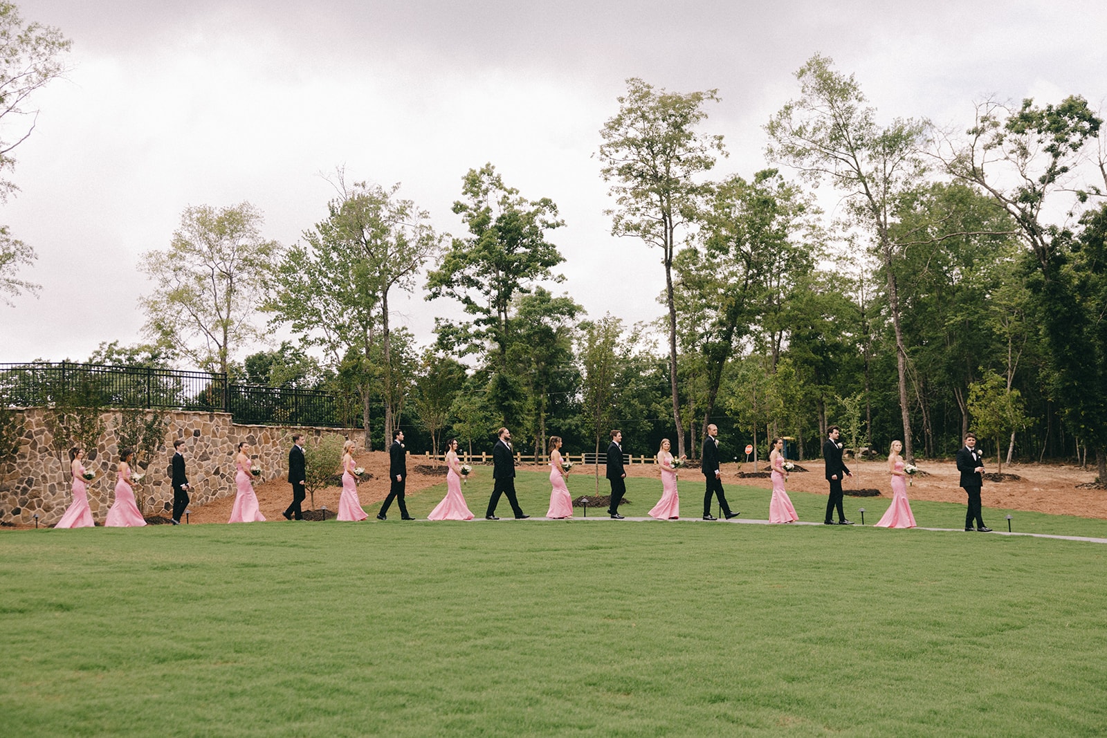 Full bridal party walking across the manicured lawn