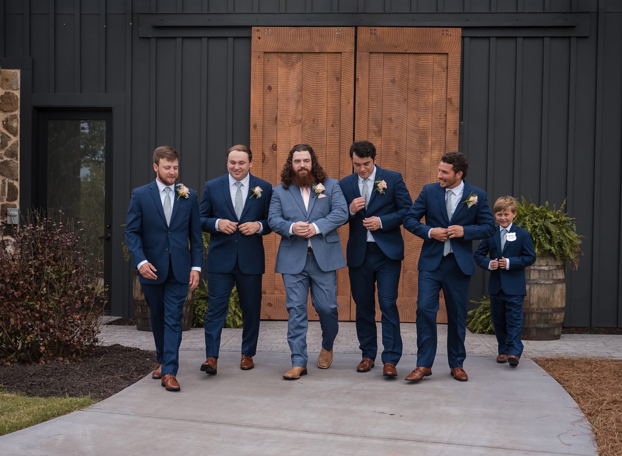 Groomsmen walking together on the lawn in front of the stone building