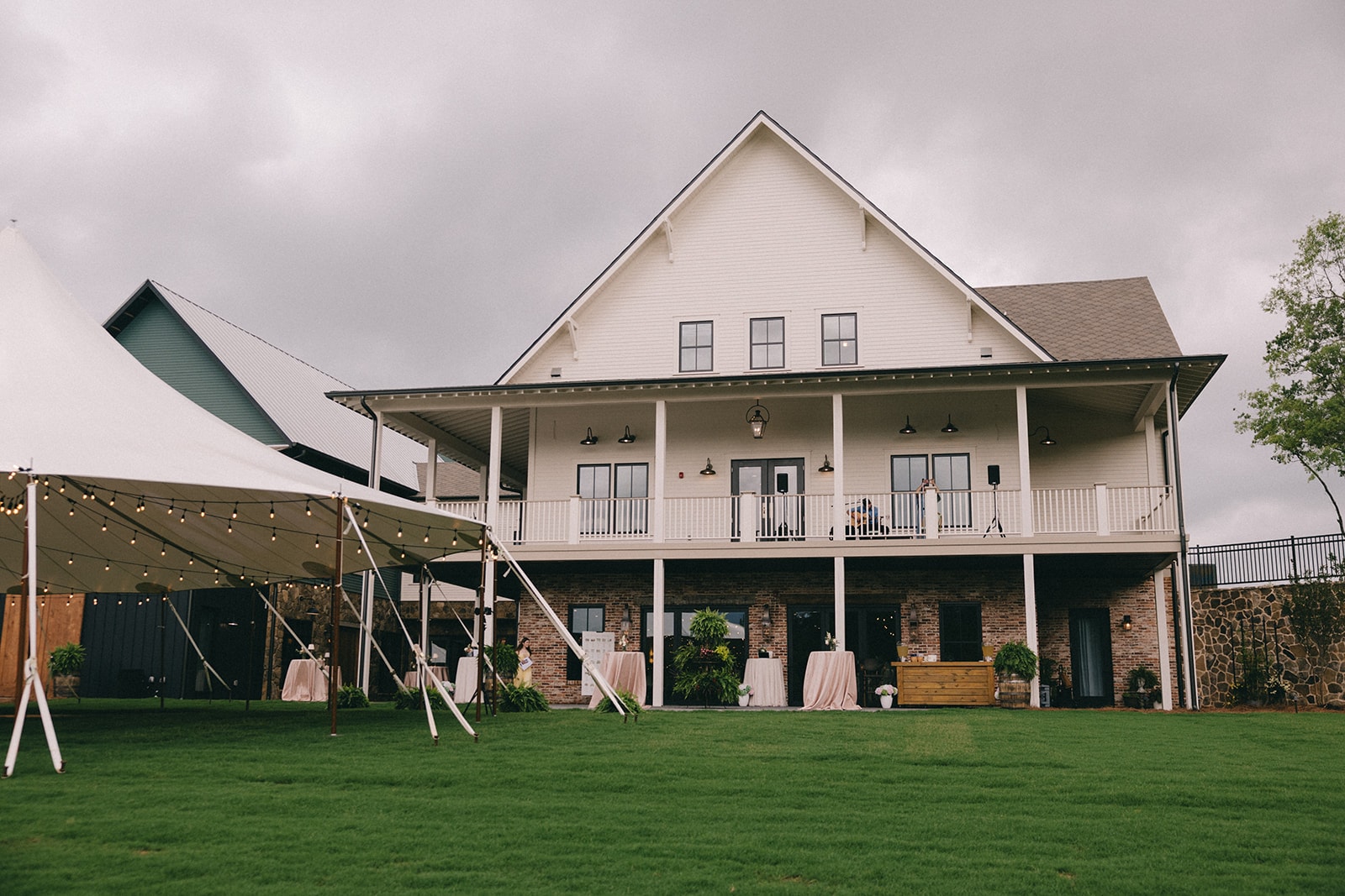 Venue exterior with tent and cocktail tables on the lawn