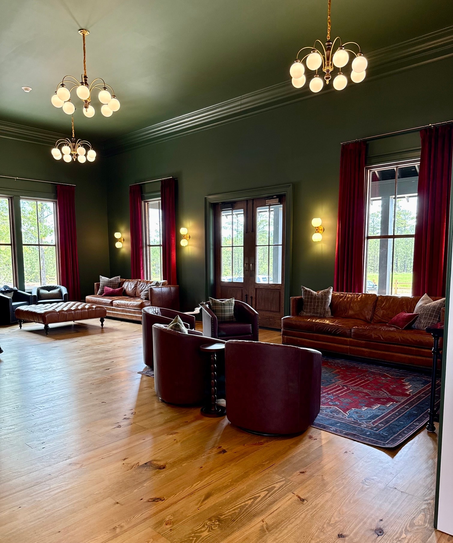 Groomsmen relaxing on leather sofas in the lounge with red velvet curtains