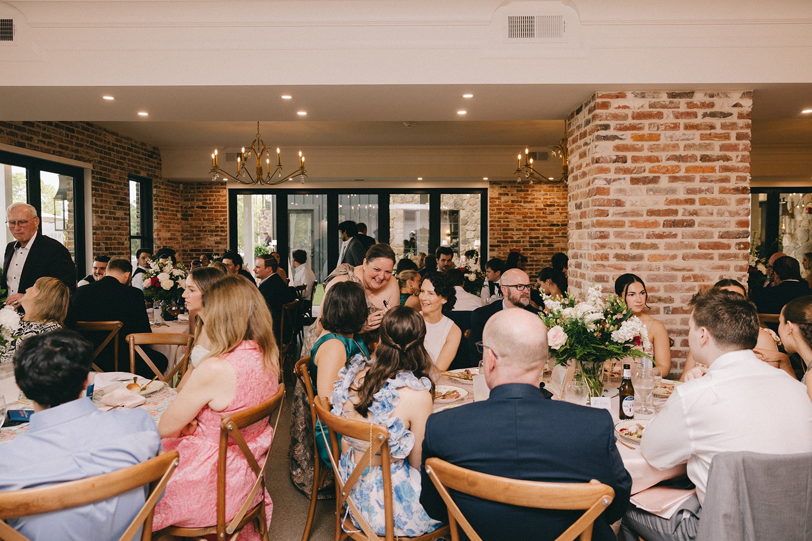 Guests dining and celebrating in the brick-walled reception hall